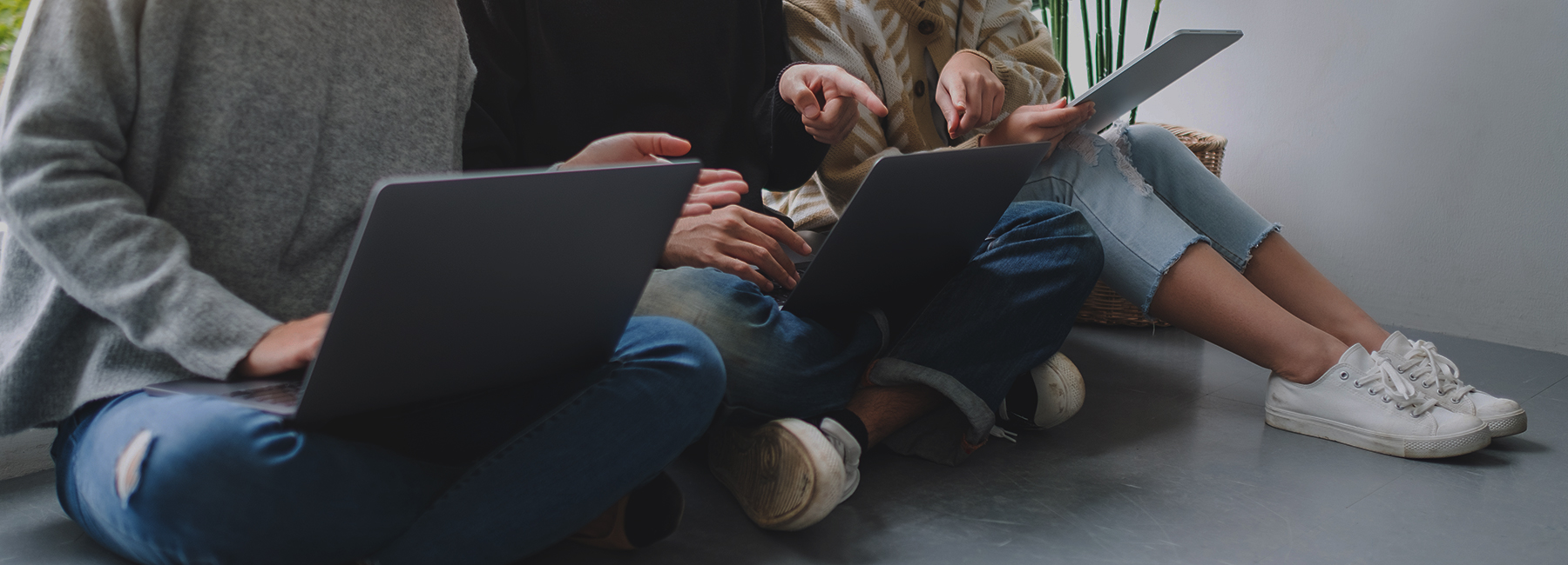 Three workers sitting on floor using laptops, Modern Device Management | DXC Technology